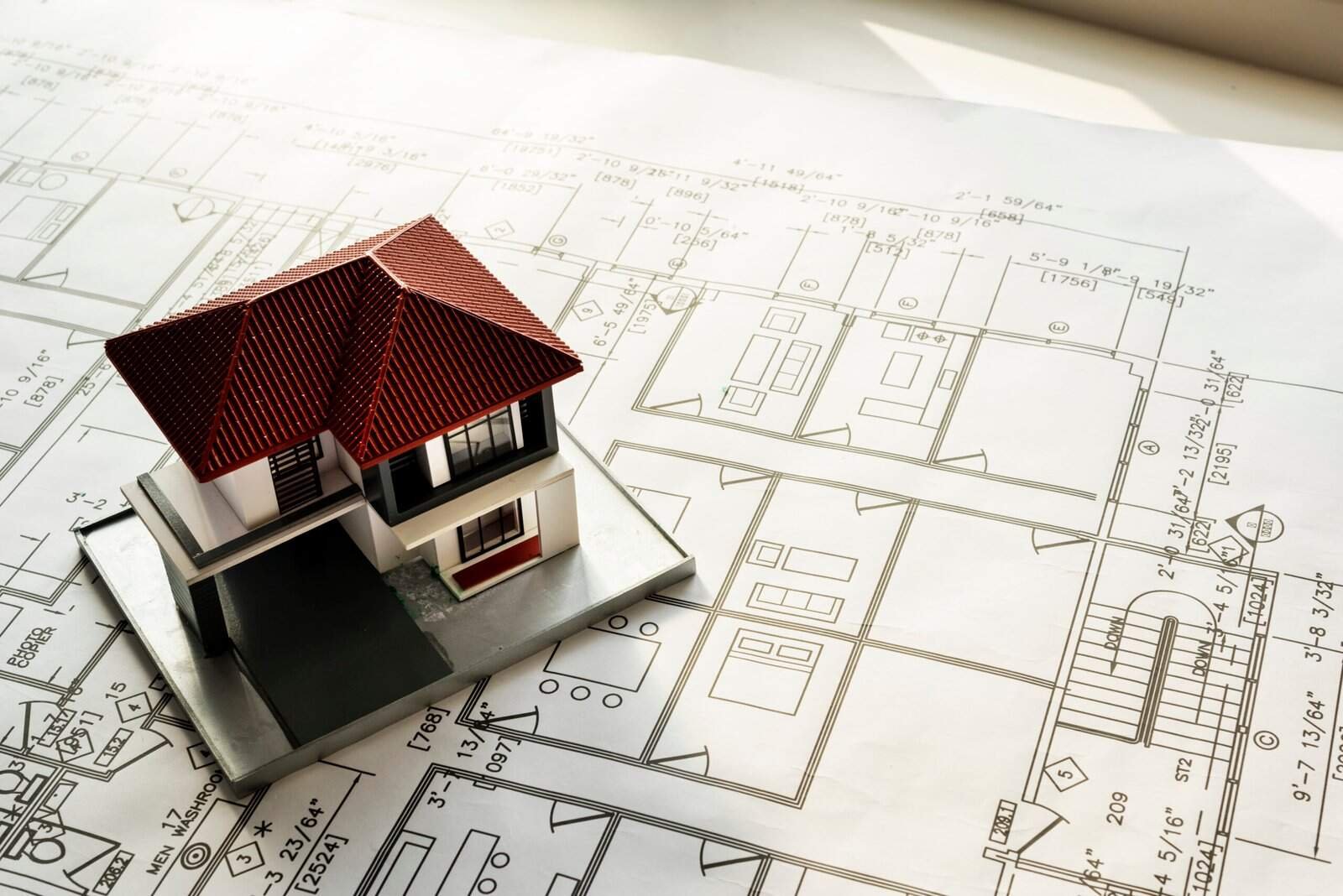 House model on detailed architectural blueprints for home design and construction planning.
