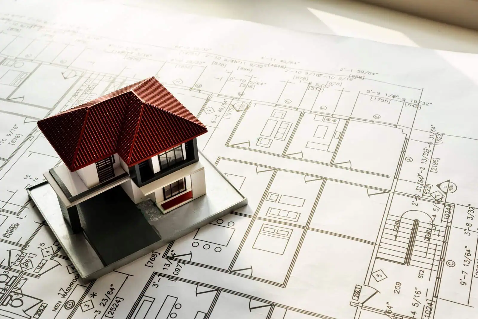 House model on detailed architectural blueprints for home design and construction planning.