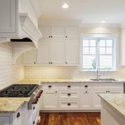 Bright modern kitchen with white cabinets, granite countertops, and large window.