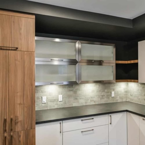 Contemporary kitchen featuring wooden cabinetry, stainless steel appliances, and a sleek black count.