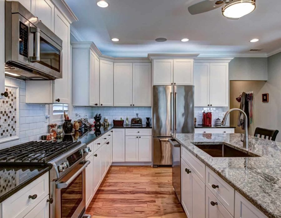 Bright, spacious kitchen featuring white cabinets, stainless steel fridge, and granite island.
